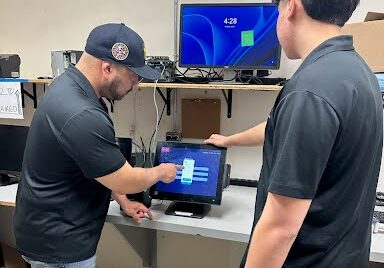 West Coast POS representative training a business owner on how to use a point of sale system.